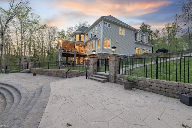 patio terrace at dusk featuring a balcony and a yard