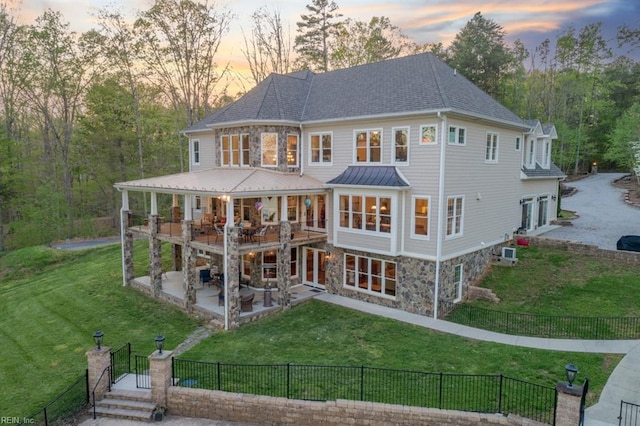 back house at dusk featuring a patio area and a yard