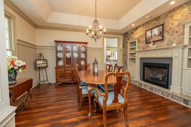 dining room with a tray ceiling, dark hardwood / wood-style flooring, a chandelier, and built in features