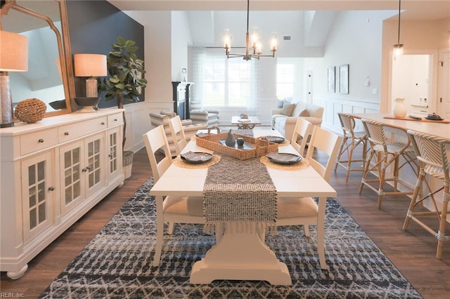 dining room with lofted ceiling, an inviting chandelier, and dark wood-type flooring