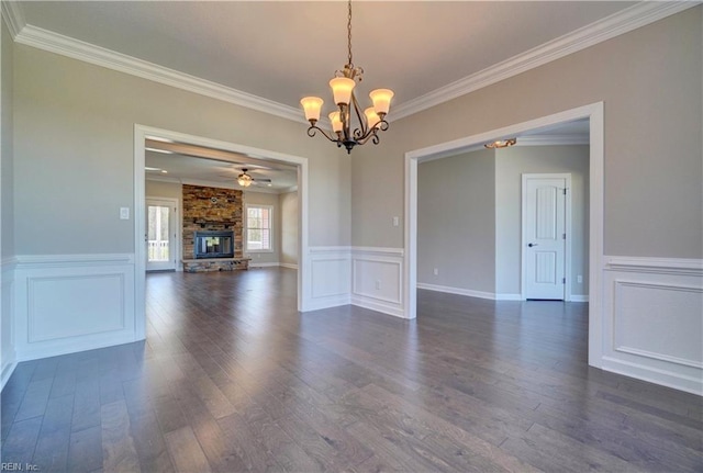 empty room with ceiling fan with notable chandelier, ornamental molding, a fireplace, and dark hardwood / wood-style flooring