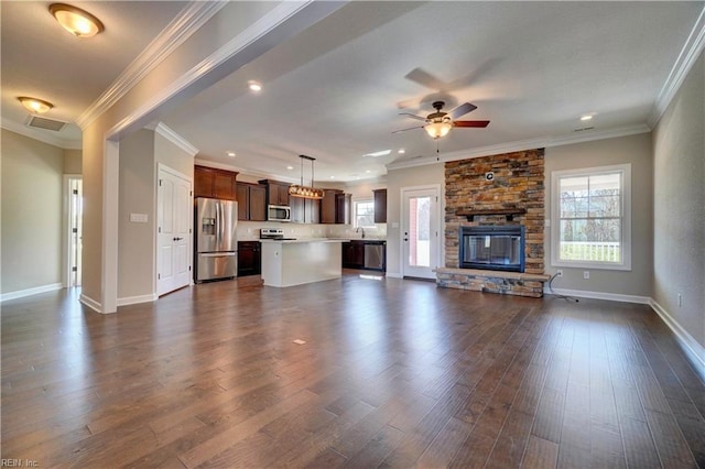 unfurnished living room featuring ceiling fan, crown molding, dark wood-type flooring, and a stone fireplace