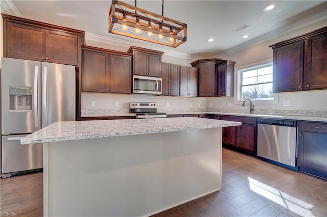 kitchen with pendant lighting, light hardwood / wood-style floors, a center island, appliances with stainless steel finishes, and crown molding