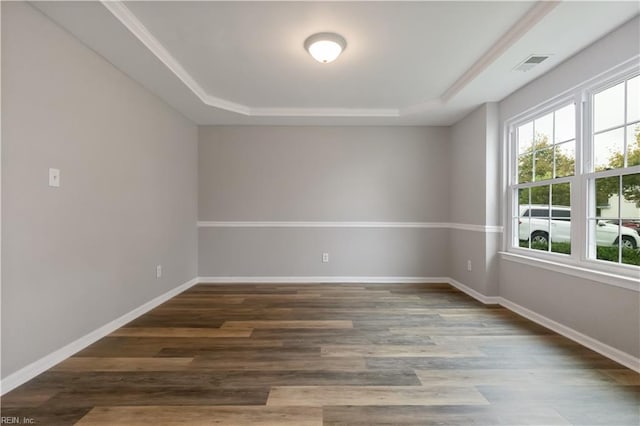 unfurnished room featuring ornamental molding, a raised ceiling, and dark wood-type flooring