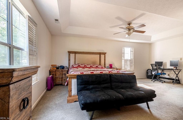 bedroom featuring ceiling fan, a raised ceiling, and light carpet