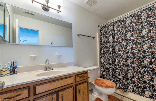 bathroom with tile patterned floors, vanity, a textured ceiling, and toilet