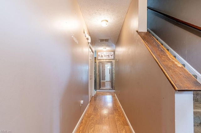 hallway with wood-type flooring and a textured ceiling