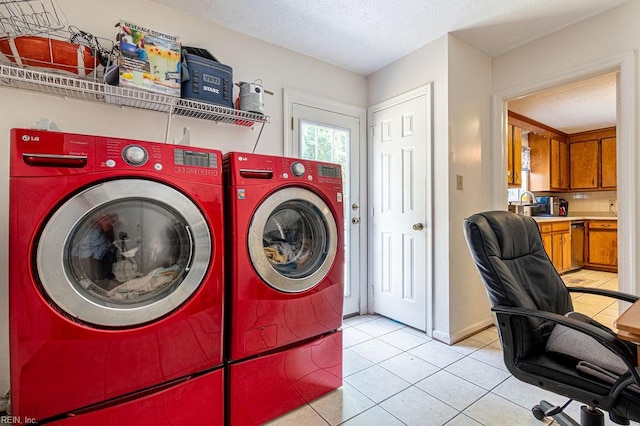 clothes washing area featuring light tile patterned floors, a textured ceiling, and washing machine and clothes dryer