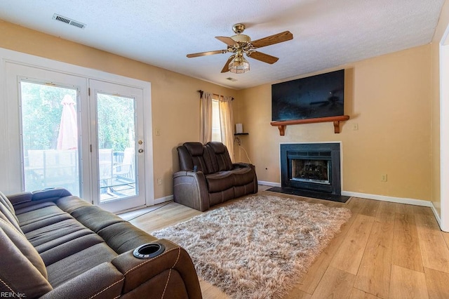 living room featuring a textured ceiling, light wood-type flooring, and ceiling fan