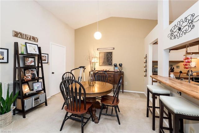 carpeted dining room featuring high vaulted ceiling