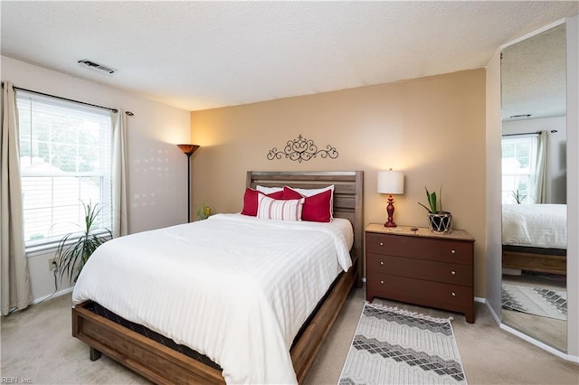 bedroom featuring a textured ceiling and light colored carpet