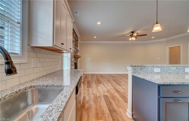 kitchen featuring light hardwood / wood-style floors, ceiling fan, decorative light fixtures, ornamental molding, and sink