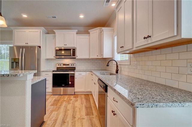 kitchen featuring pendant lighting, stainless steel appliances, light wood-type flooring, and white cabinetry