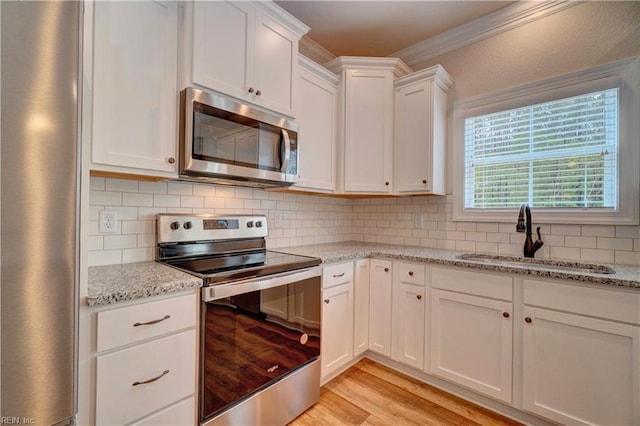 kitchen with sink, white cabinets, light hardwood / wood-style flooring, stainless steel appliances, and crown molding