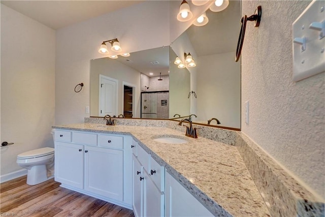 bathroom featuring hardwood / wood-style floors, tiled shower, vanity, and toilet