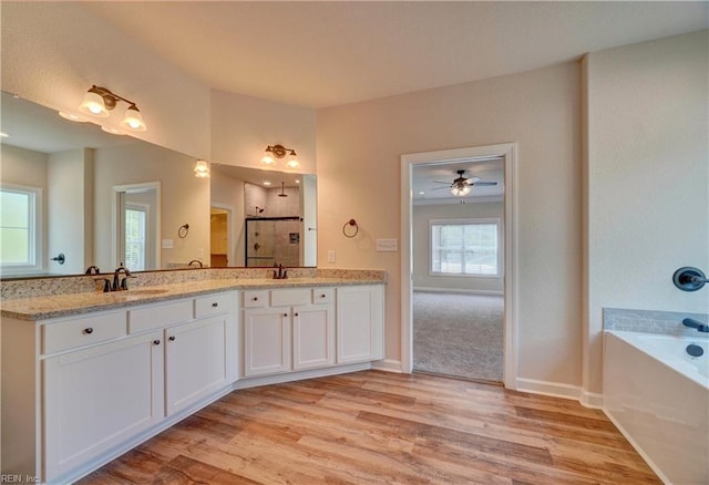 bathroom featuring wood-type flooring, vanity, plus walk in shower, and ceiling fan