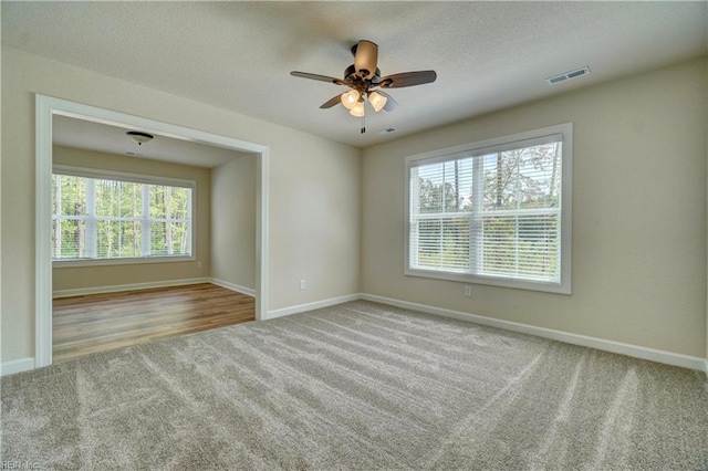 empty room featuring a textured ceiling, light hardwood / wood-style floors, ceiling fan, and a wealth of natural light