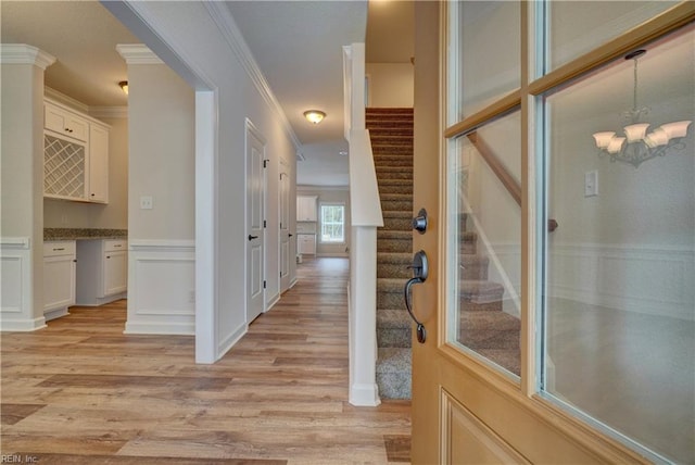 hallway featuring crown molding, light hardwood / wood-style flooring, and a notable chandelier