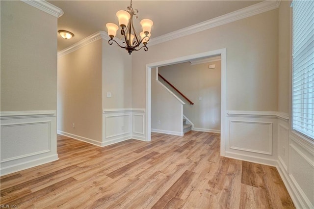 empty room with crown molding, light hardwood / wood-style floors, and an inviting chandelier