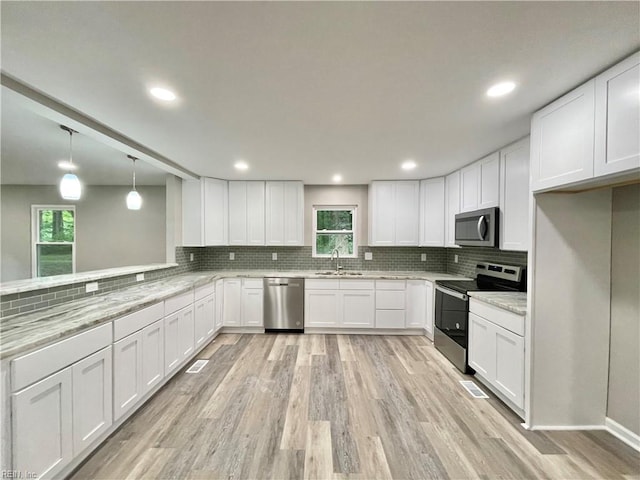 kitchen with pendant lighting, white cabinets, a wealth of natural light, and appliances with stainless steel finishes