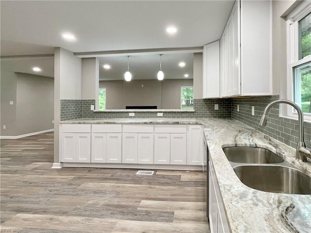 kitchen with pendant lighting, sink, light hardwood / wood-style flooring, backsplash, and white cabinetry