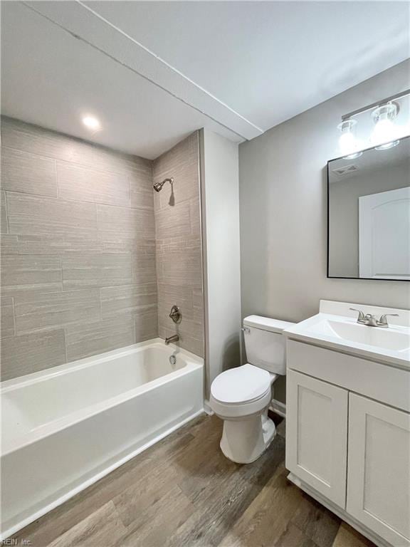 full bathroom with vanity, hardwood / wood-style flooring, tiled shower / bath, and toilet