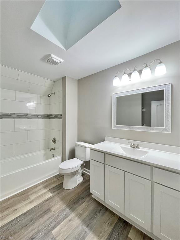 full bathroom with hardwood / wood-style flooring, vanity, toilet, and tiled shower / bath