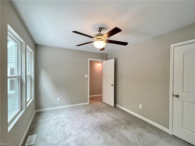 unfurnished bedroom featuring ceiling fan, light colored carpet, and multiple windows