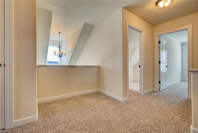 hall featuring carpet flooring and an inviting chandelier