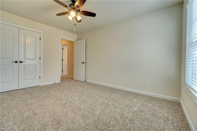 unfurnished bedroom featuring ceiling fan, light colored carpet, and a closet