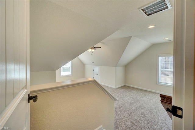 additional living space featuring vaulted ceiling, ceiling fan, light colored carpet, and plenty of natural light