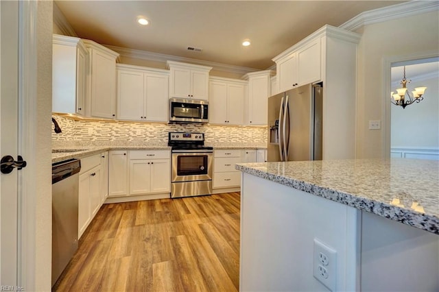 kitchen with appliances with stainless steel finishes, light stone counters, white cabinets, light hardwood / wood-style flooring, and a chandelier