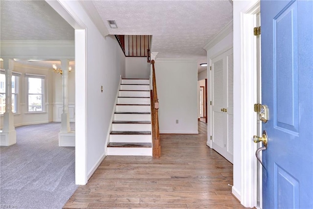 entryway featuring an inviting chandelier, a textured ceiling, hardwood / wood-style floors, and crown molding