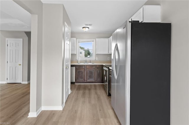 kitchen with stainless steel appliances, white cabinets, light wood-type flooring, and sink