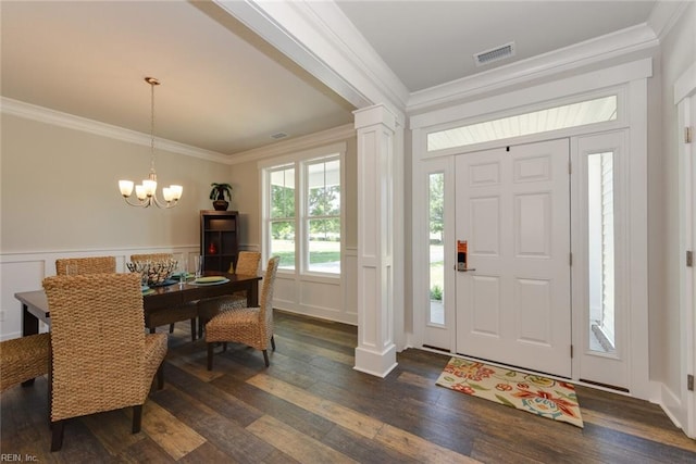 foyer featuring ornamental molding, a notable chandelier, decorative columns, and dark hardwood / wood-style flooring