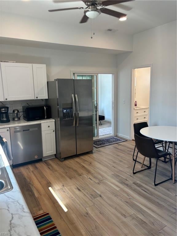 kitchen with light wood-type flooring, white cabinetry, ceiling fan, and appliances with stainless steel finishes