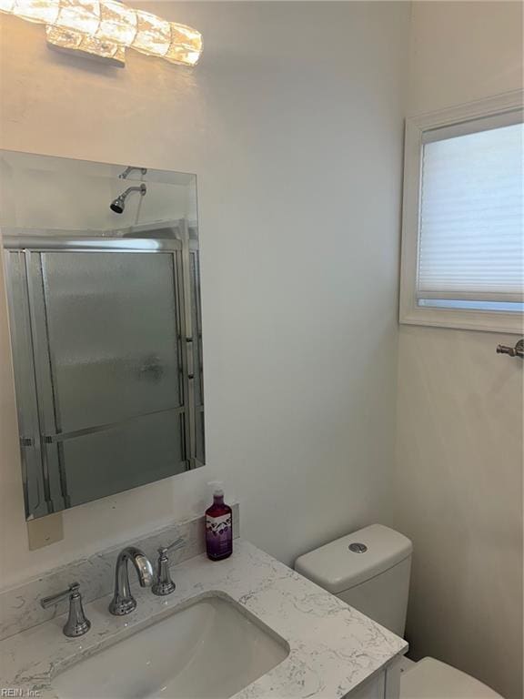 bathroom with an enclosed shower, vanity, and toilet