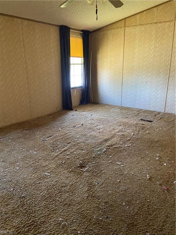 empty room with lofted ceiling, a textured ceiling, and ceiling fan