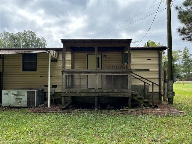 rear view of property with central AC unit and a yard