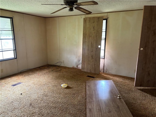 unfurnished room with ceiling fan, a textured ceiling, and carpet