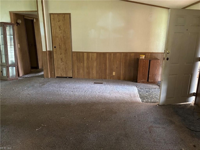 carpeted empty room with wooden walls