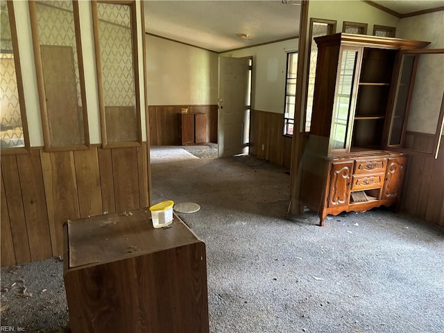 hallway featuring carpet, wood walls, and a textured ceiling