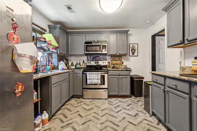 kitchen featuring gray cabinets, appliances with stainless steel finishes, and sink