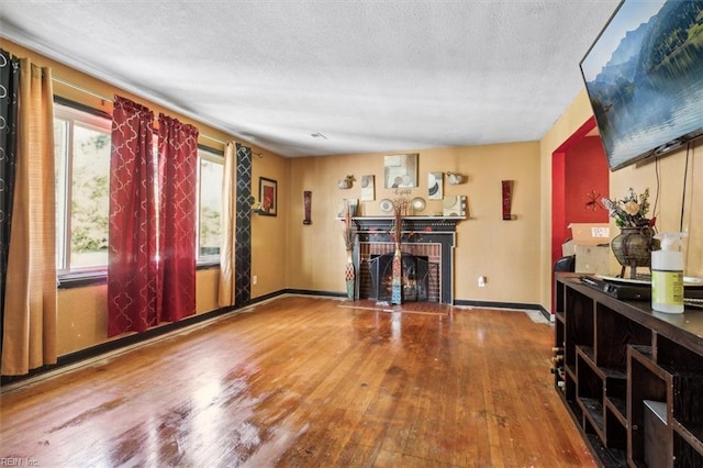 interior space featuring a brick fireplace, a textured ceiling, and hardwood / wood-style flooring