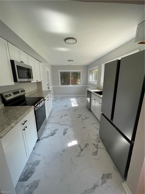 kitchen featuring white cabinets, stainless steel appliances, and light stone countertops