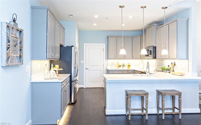 kitchen featuring pendant lighting, sink, appliances with stainless steel finishes, and dark wood-type flooring