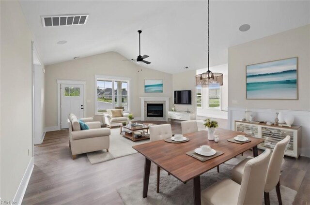 dining room with ceiling fan with notable chandelier, lofted ceiling, and wood-type flooring