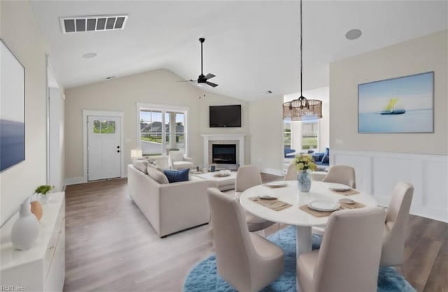 dining room featuring light hardwood / wood-style floors, ceiling fan with notable chandelier, and lofted ceiling