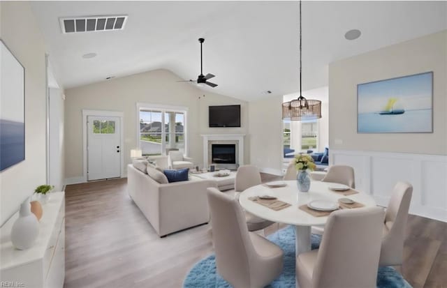 dining space featuring light hardwood / wood-style floors, ceiling fan with notable chandelier, and vaulted ceiling