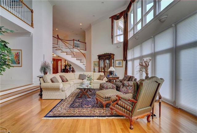 living room with hardwood / wood-style floors, crown molding, and a towering ceiling